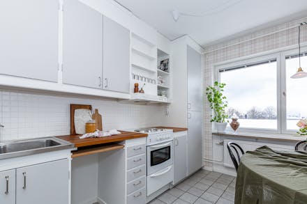 Rymligt kök med matplats invid fönster samt klinkergolv
