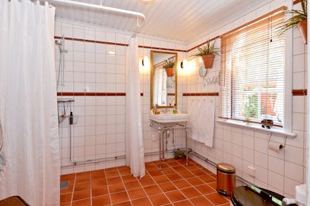 Stort och praktiskt badrum med wc, tvättställ, dusch och fönster