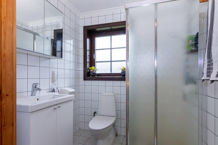 Badrum på nedre plan med dusch och helkaklade väggar.