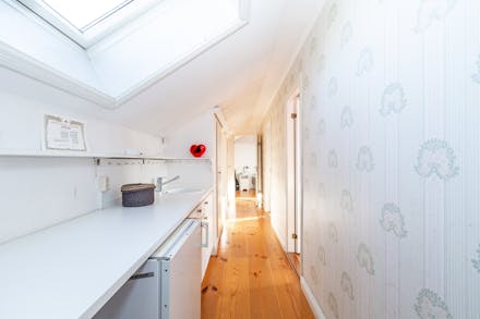 Hall/passage med takfönster, tvättställ och kyl som leder in i sovrumsdel med 3 sovrum.